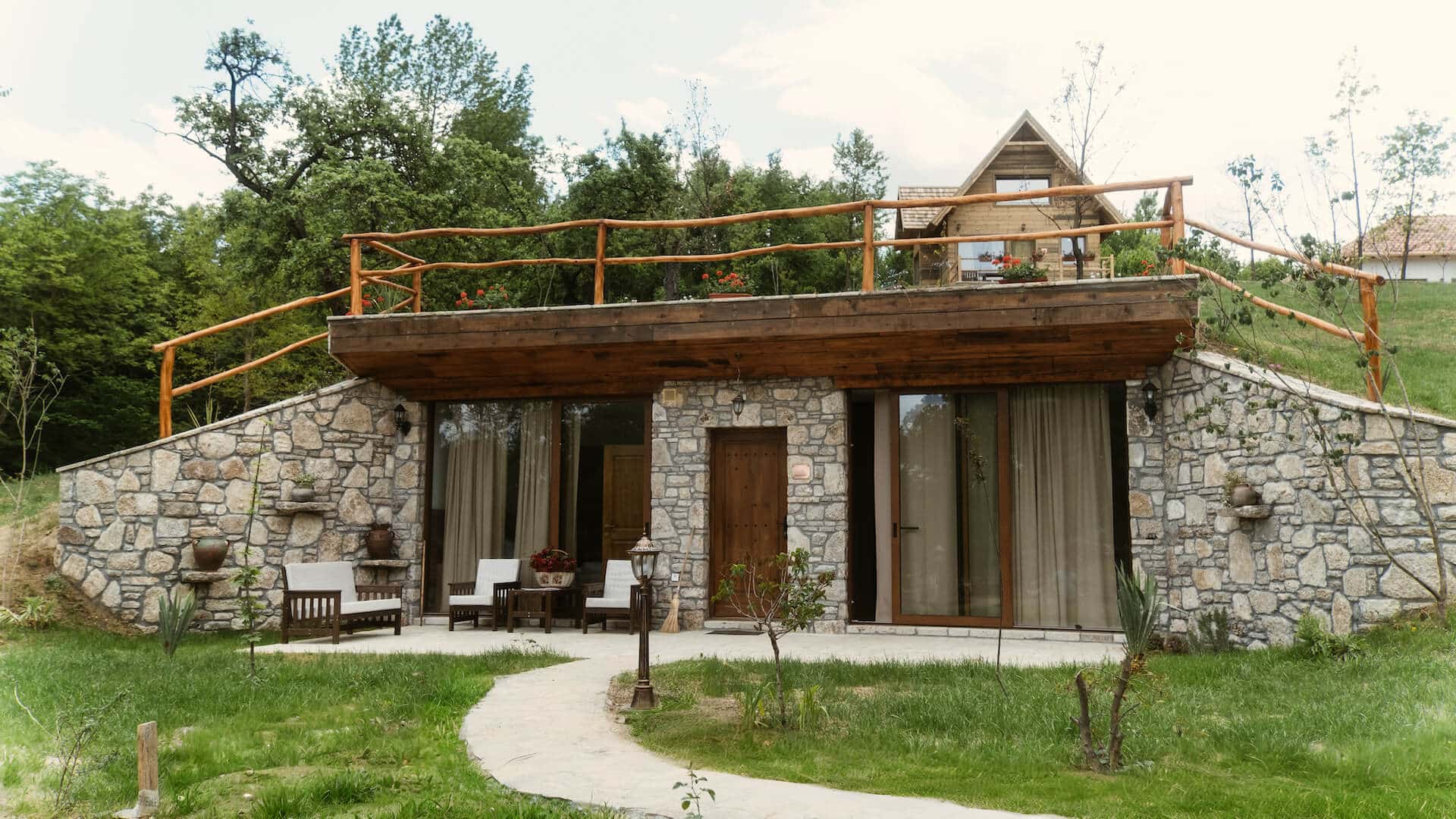 Kamena kuća ukopana u padinu sa drvenom terasom